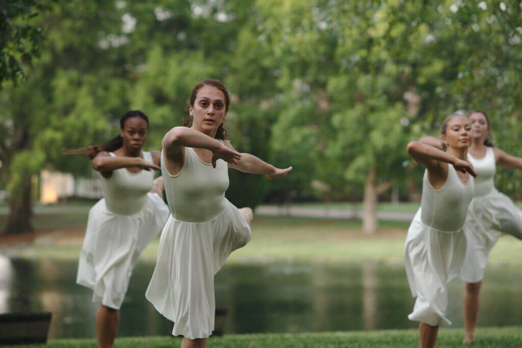 Dance students performing in front of a lake.
