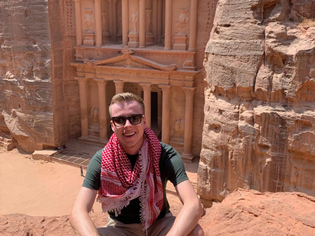 Spencer Rieser posing in front of buildings whily studying abroad in Jordan.