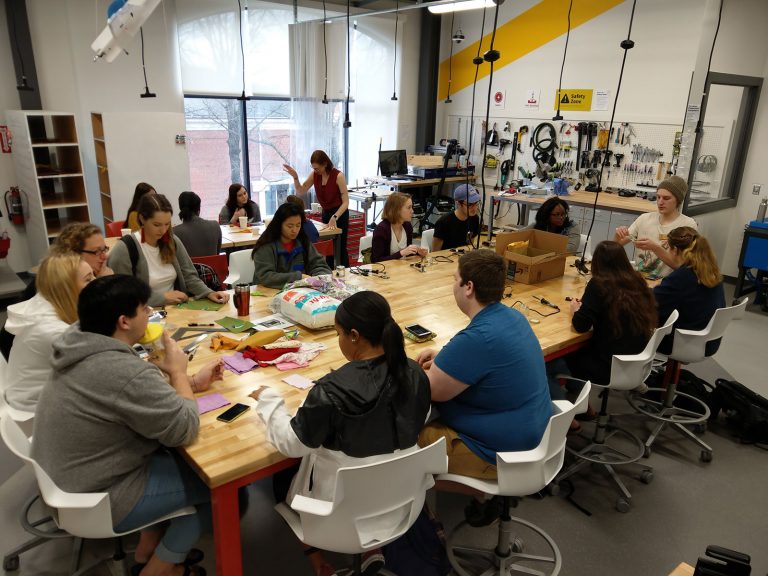 Students gather around a table in the Maker Hub to work on projects.