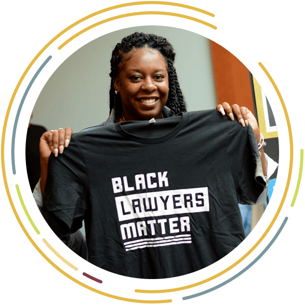 Woman holding up Black Lawyers Matter shirt.