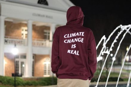 A man looking at fountain with back of his sweatshirt reading "CLIMATE CHANGE IS REAL."