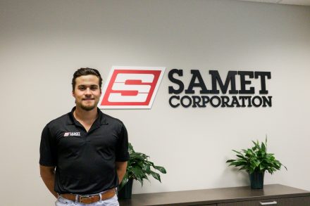 man standing in front of Samet Corporation sign