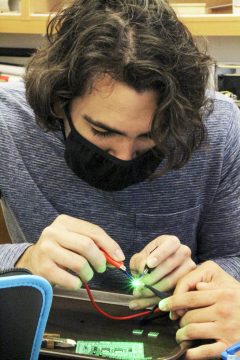 Matthew Del Valle '21 tests a LED light before soldering it to a circuit board as part of the engineering program's senior capstone project.