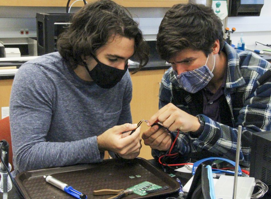 Matthew Del Valle '21, left, and Eduardo Gonzalez '21 work together to test circuits and LED lights as they design an optical sensor that will measure water turbidity.