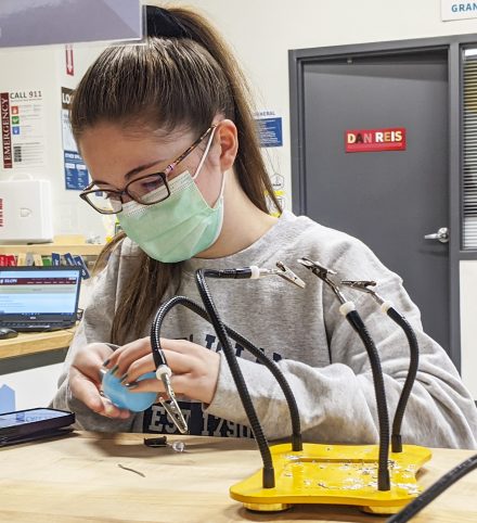Sophie David '24 solders the circuit for a flip light in the Maker Hub during an Elon College Fellows activity.