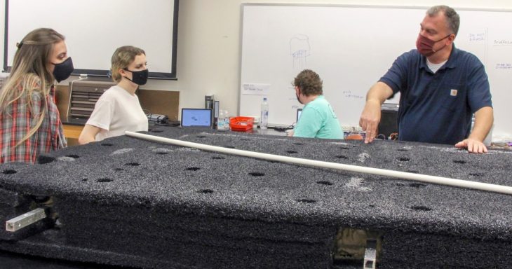 Associate Professor of Engineering Scott Wolter examines a floating wetlands platform with engineering seniors. Seniors will deploy the platform this spring equipped with sensors and vegetation to monitor and improve water quality. 