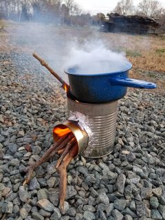 A small fire burns in a rocket stove as water boils in a pot