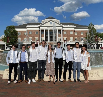 Nine students standing in front of the Koury Busines Center