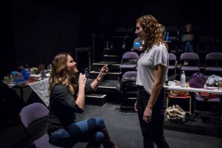 Kim Shively gestures towards student Christine Lane in a theatre space.